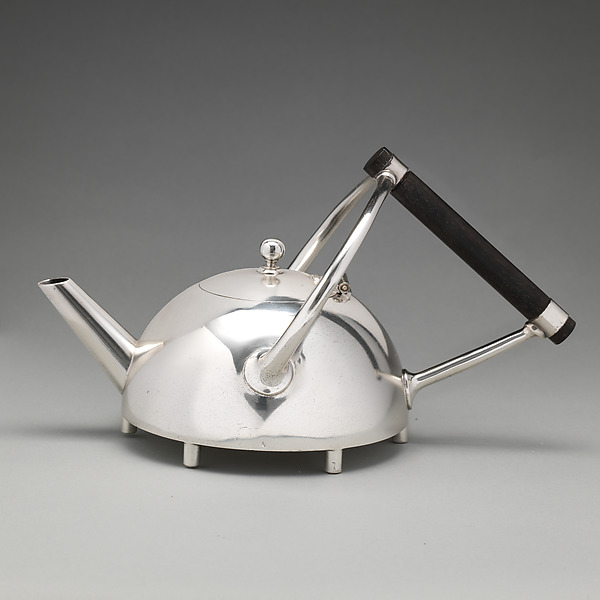 A low silver-plated teapot with an angled spout, small feet and a triangular structure holding an ebony handle